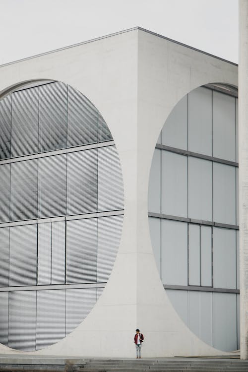 Person Standing near Corner of White, Modern Building