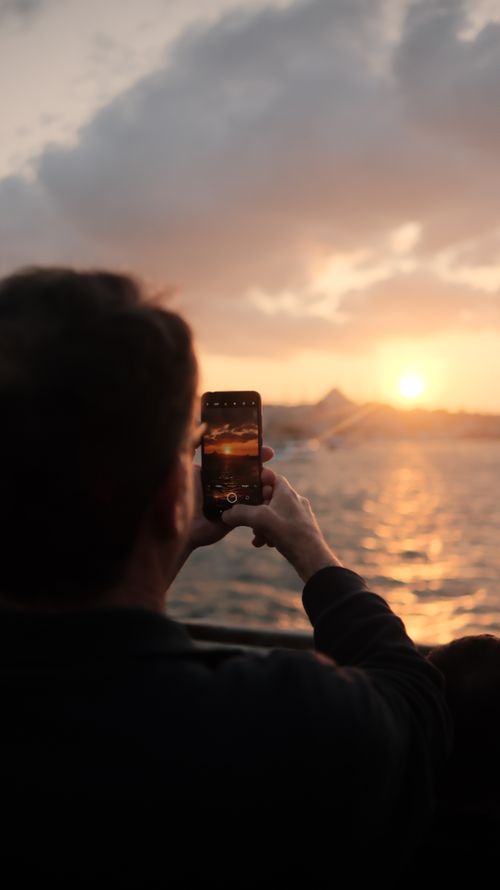 Free A woman photographs the scenic Istanbul sunset by the sea, emphasizing travel and technology. Stock Photo
