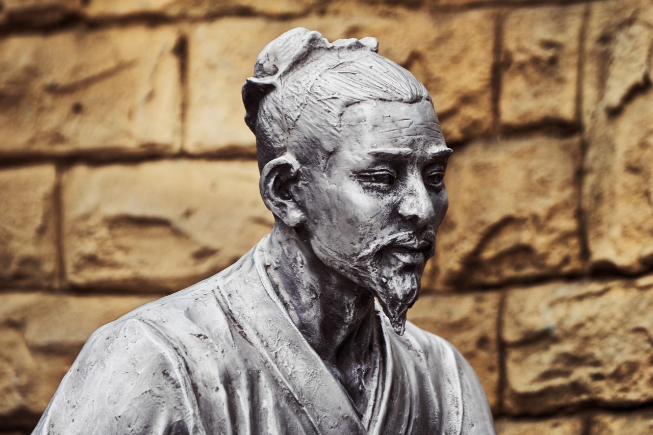 a detailed bronze sculpture of a historical figure set against a textu