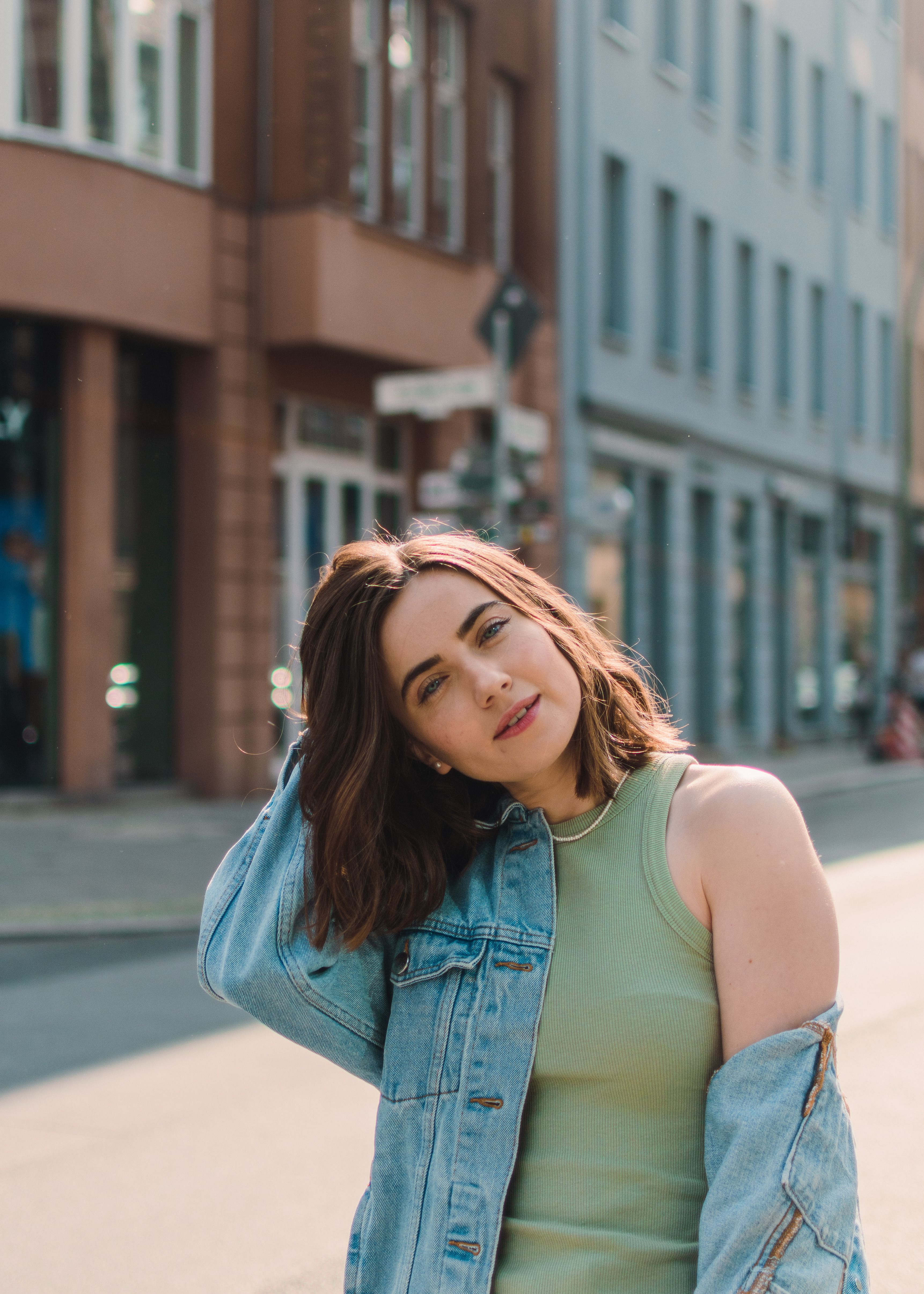 Young woman in a denim jacket posing confidently on a city street.