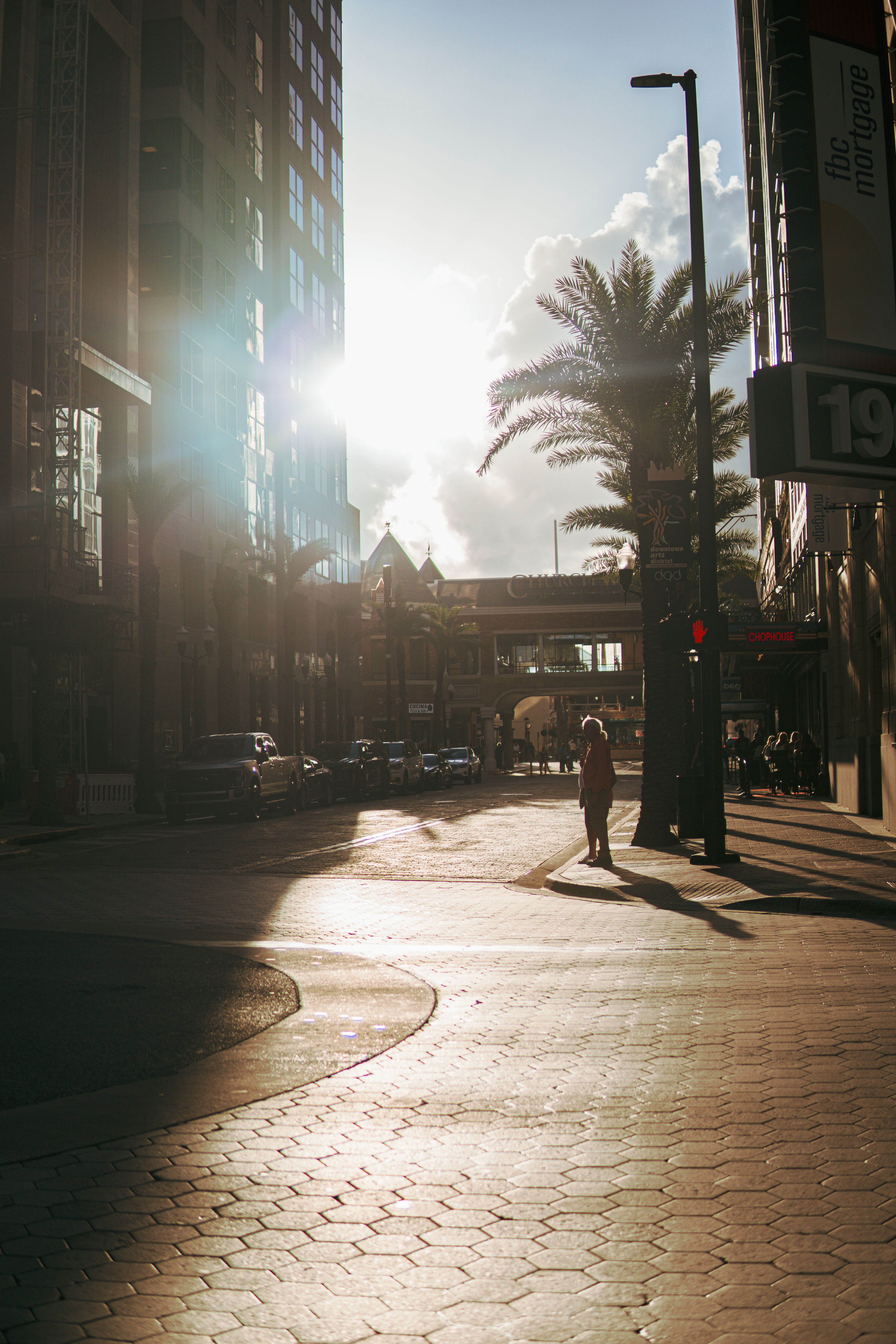 Sunset in downtown Orlando showcasing urban architecture and a silhouetted pedestrian crossing.