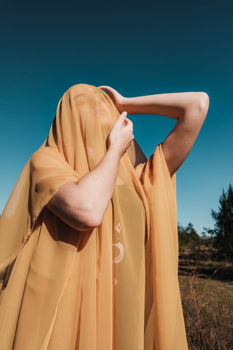 Woman Covered In Yellow Sheer Fabric Posing Outside 