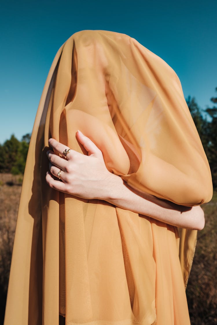 Woman Covered In Yellow Sheer Fabric Posing Outside 