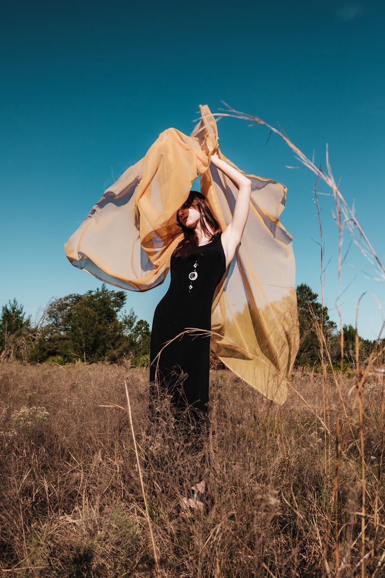 Woman Holding Yellow Sheer Fabric Posing Outside 