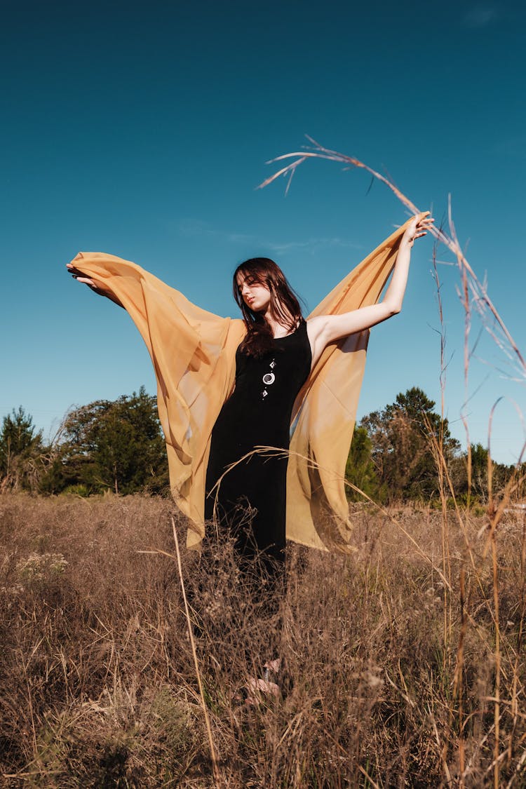 Woman Holding Yellow Sheer Fabric Posing Outside 