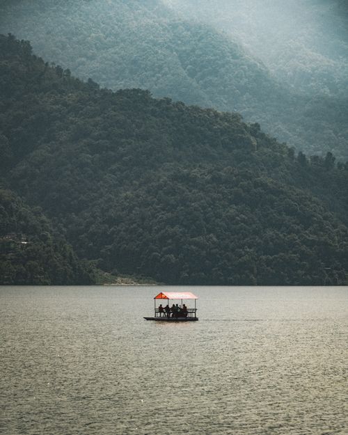 Free A serene boat ride on a tranquil lake surrounded by lush mountains under a gentle sky. Stock Photo