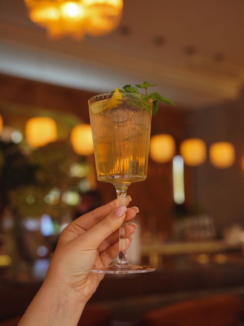 Free A hand holds a refreshing cocktail with lemon garnish at an upscale bar, evoking a sense of elegance and celebration. Stock Photo