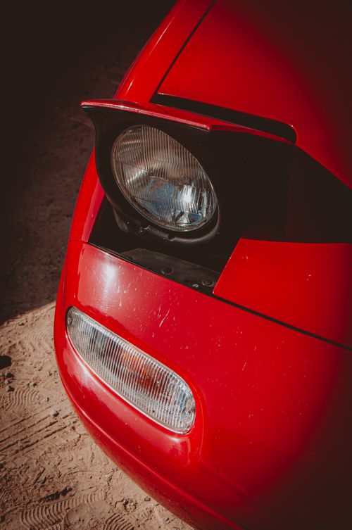 Free Vintage red car with pop-up headlight in sunlight, highlighting its classic design. Stock Photo