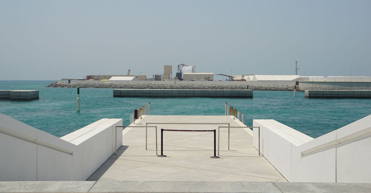 View of a modern seaside walkway with clear blue waters in Abu Dhabi.