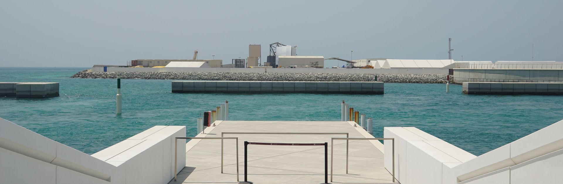 View of a modern seaside walkway with clear blue waters in Abu Dhabi.