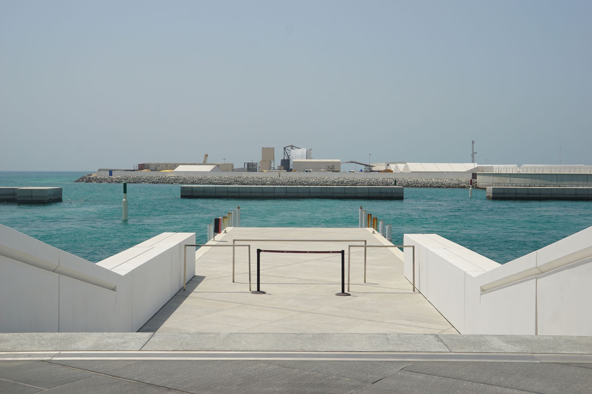 View of a modern seaside walkway with clear blue waters in Abu Dhabi.