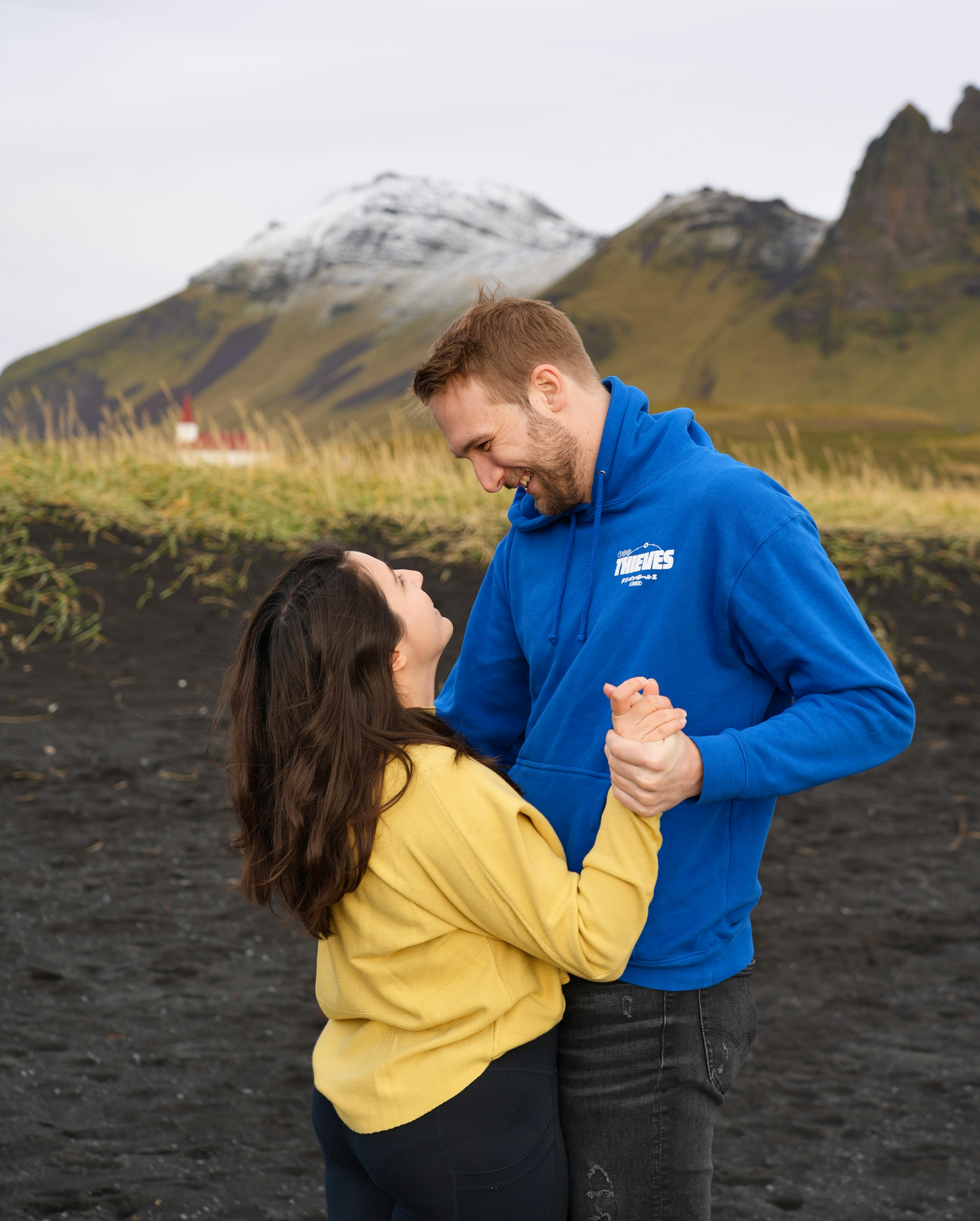 A couple joyfully embraces on the picturesque black sand beach of Vik, Iceland.