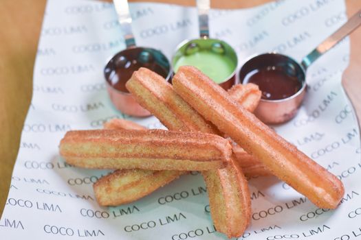 Close-up view of fresh churros with sauces, ideal for dessert lovers and food photographers.