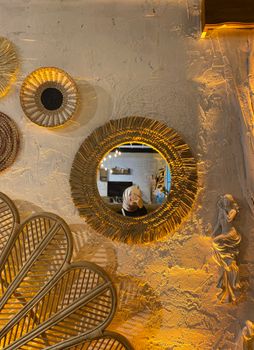 Artistic wall decorated with woven baskets, a mirror, and sculpture in warm lighting.