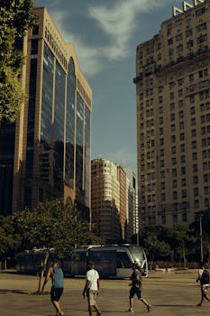 A bustling urban street with people walking and a tram passing by tall skyscrapers.