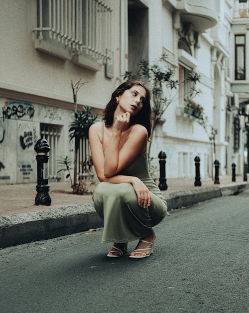 Model in Green Dress Squatting and Thinking on Street