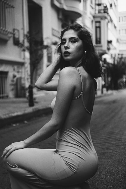 Model in Dress Squatting on Street