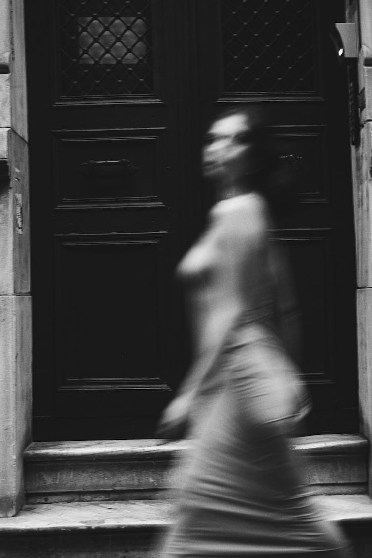 Blurred Woman Walking By Door In Black And White