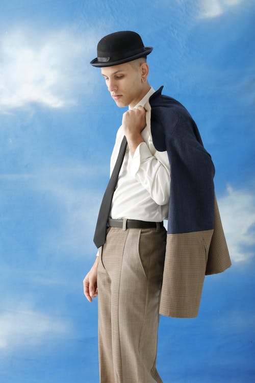 Person Wearing Bowler Hat Posing in Studio in front of Blue Sky Background