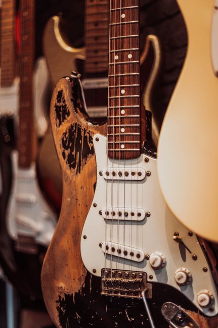 Close-up of a weathered electric guitar among others, showcasing its vintage charm.
