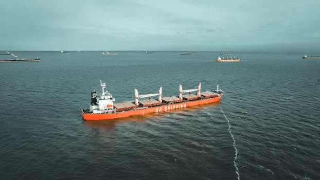 Drone view of a cargo ship navigating the ocean, showcasing maritime transport.