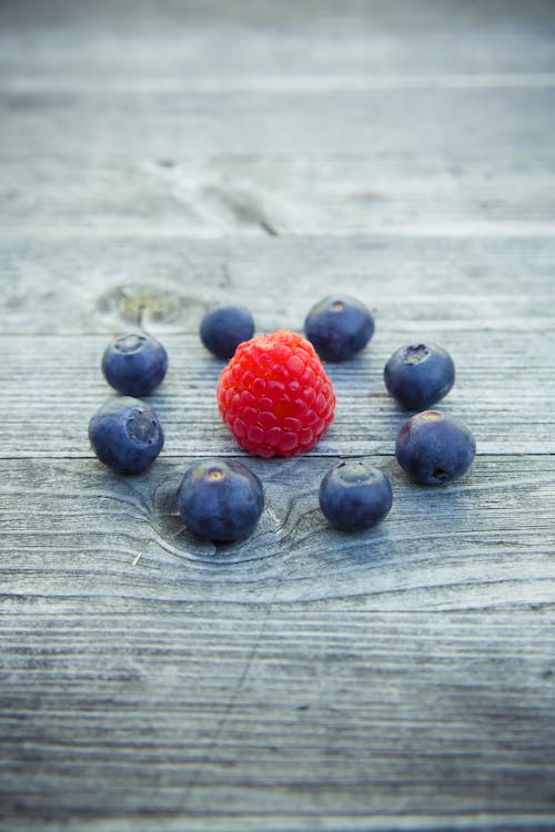 Blue and Red Berries on Gray Wooden Surface