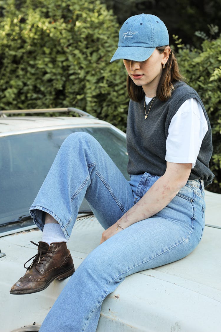 Woman In Cap Sitting On Car