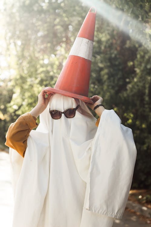 Person Dressed as a Ghost Holding a Traffic Cone on Their Head