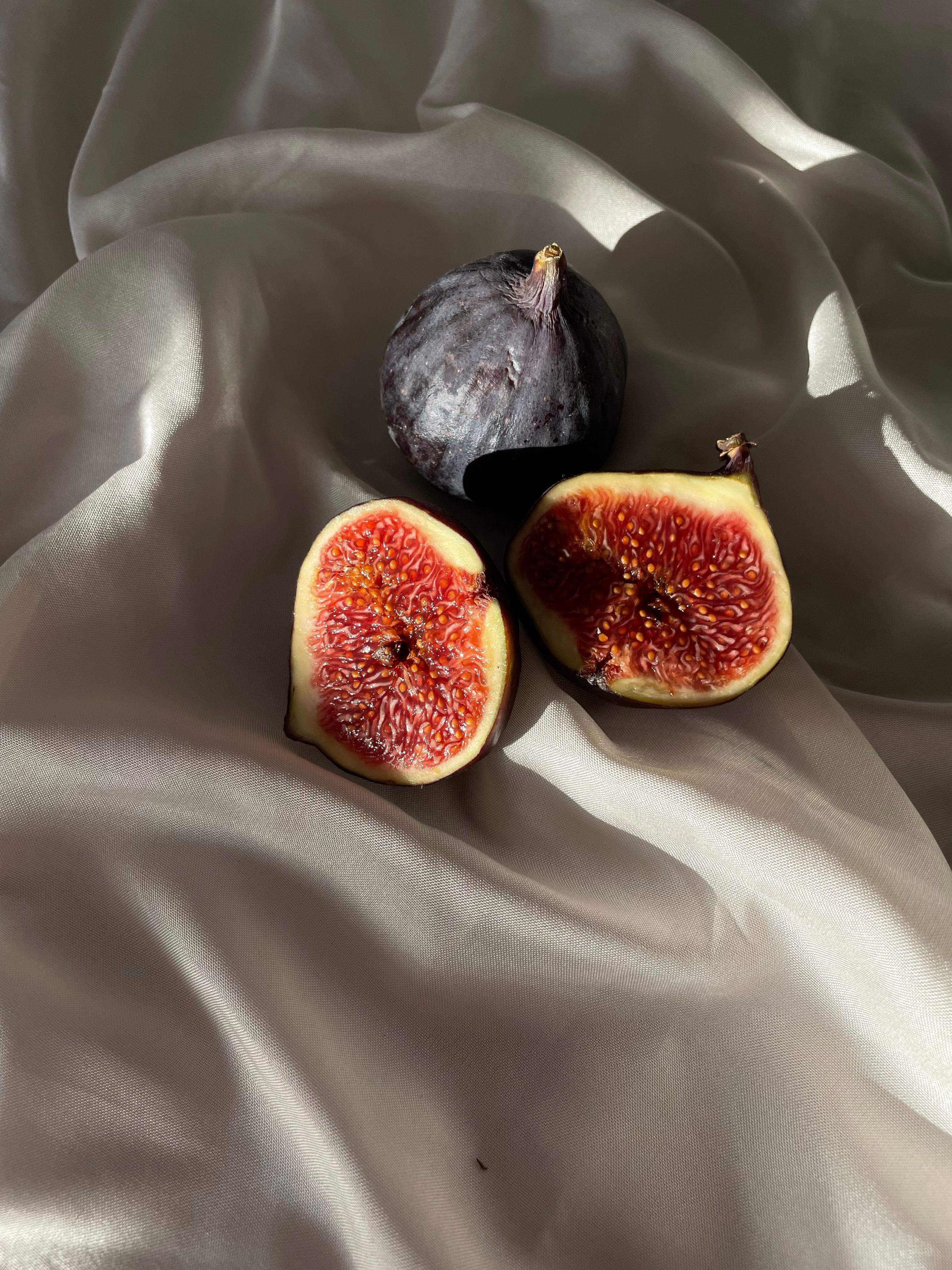 Elegant close-up of fresh figs on a smooth silk fabric background, highlighting texture and color.