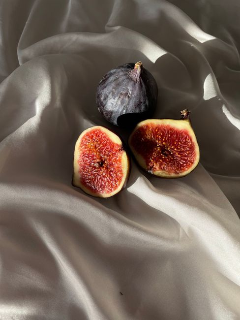 Elegant close-up of fresh figs on a smooth silk fabric background, highlighting texture and color.