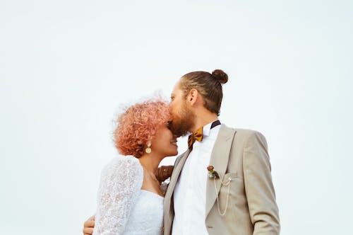 A bride and groom kiss in front of a white background