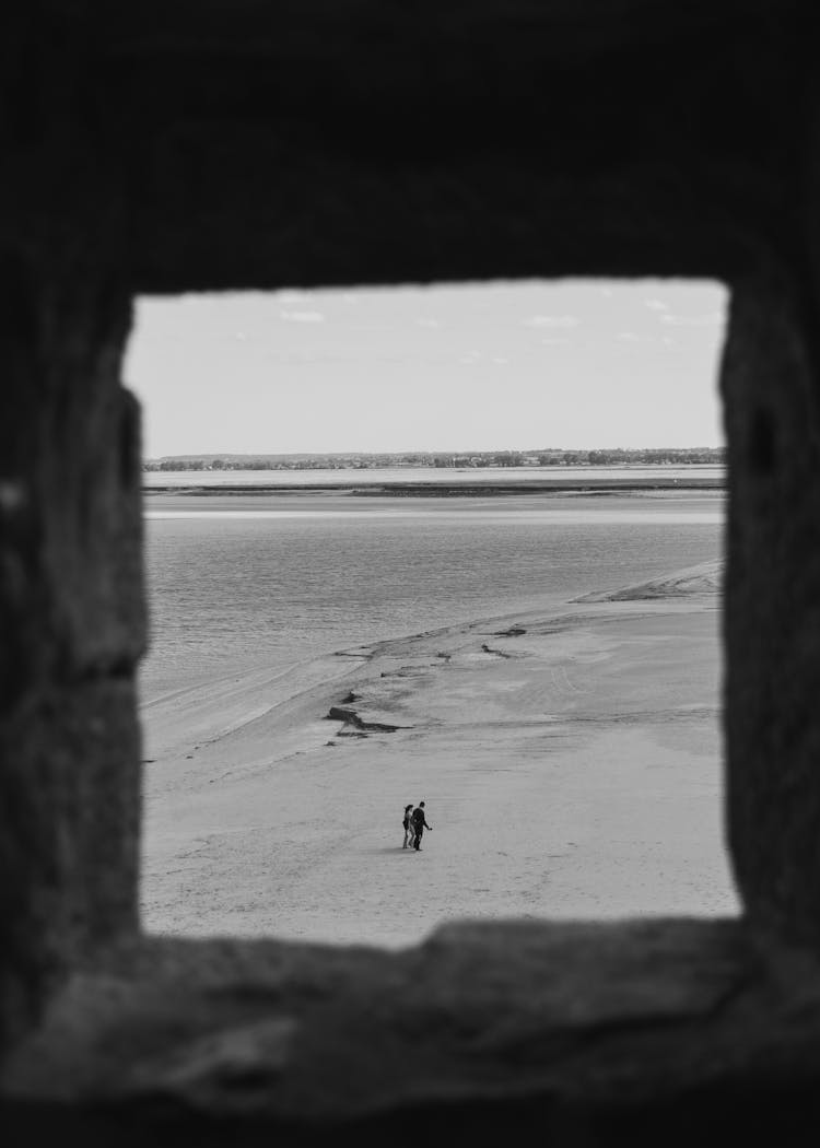 People Walking On The Beach Seen From A Window In Distance 