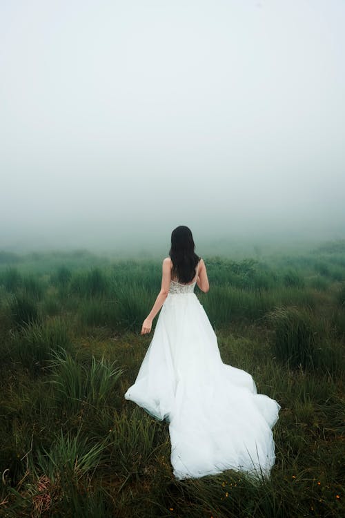 Bride in Wedding Dress on Grassland under Fog