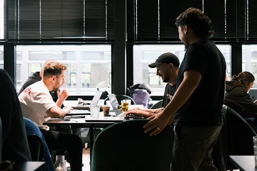 Men working together on laptops in a modern office environment, collaborating and smiling.