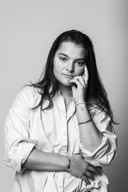Free Black and white portrait of a woman in a thoughtful pose wearing a white shirt. Stock Photo