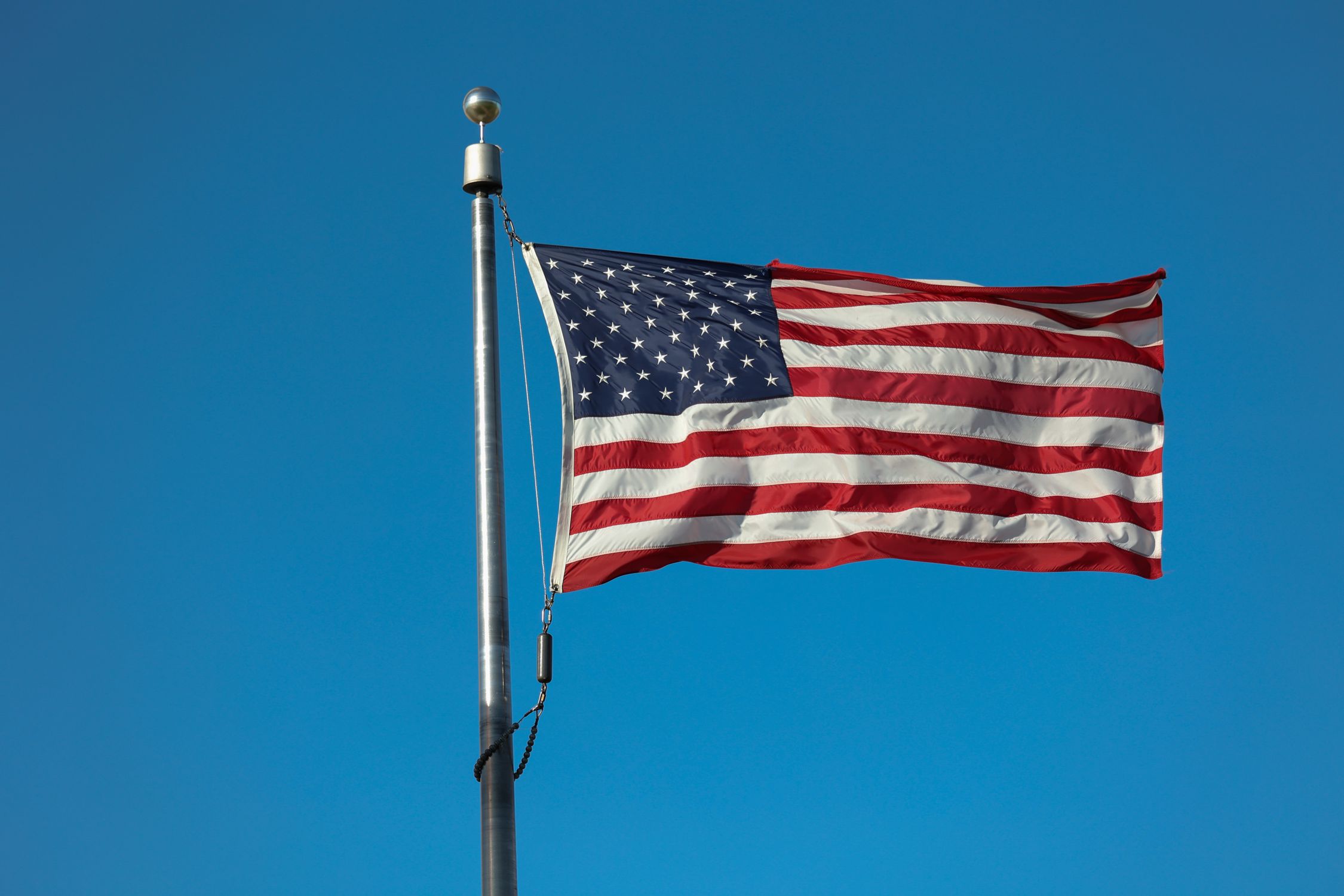 American Flag against a Clear Blue Sky · Free Stock Photo