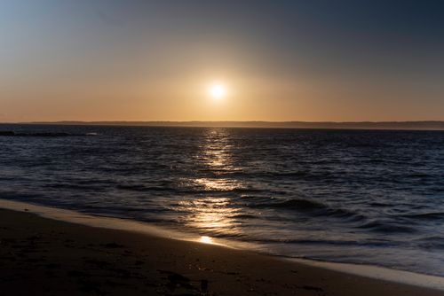 Free Golden sunset reflecting on the tranquil sea at a peaceful beach. Stock Photo