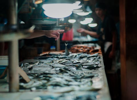 A bustling fish market showcasing fresh seafood under warm lights with customer interaction.
