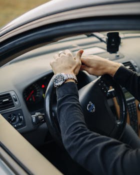 Close-up of a driver with wristwatch holding the steering wheel inside a Volvo car.