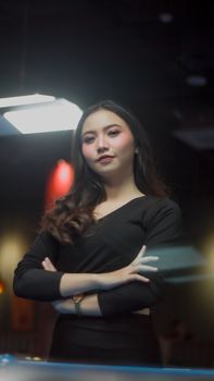 Portrait of a confident woman standing by a pool table indoors, exuding strength and poise.