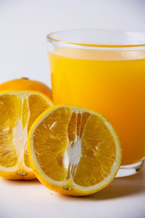Free A refreshing glass of freshly squeezed orange juice beside halved oranges, showcasing freshness and vitality. Stock Photo