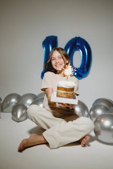 Cheerful child celebrating their 10th birthday with cake and blue balloon decorations.