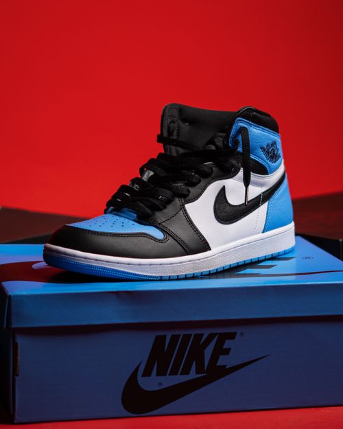 Free High-top black and blue sneaker displayed on a box with a red background. Stock Photo