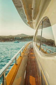View from a luxury yacht deck with sea and coastline reflections under a sunny day.