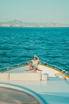 A man enjoying leisure time on the deck of a yacht with a scenic coastal backdrop.