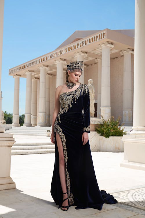 Model in Black Velvet Evening Dress with Slit and Golden Embroidery by the Ancient Temple