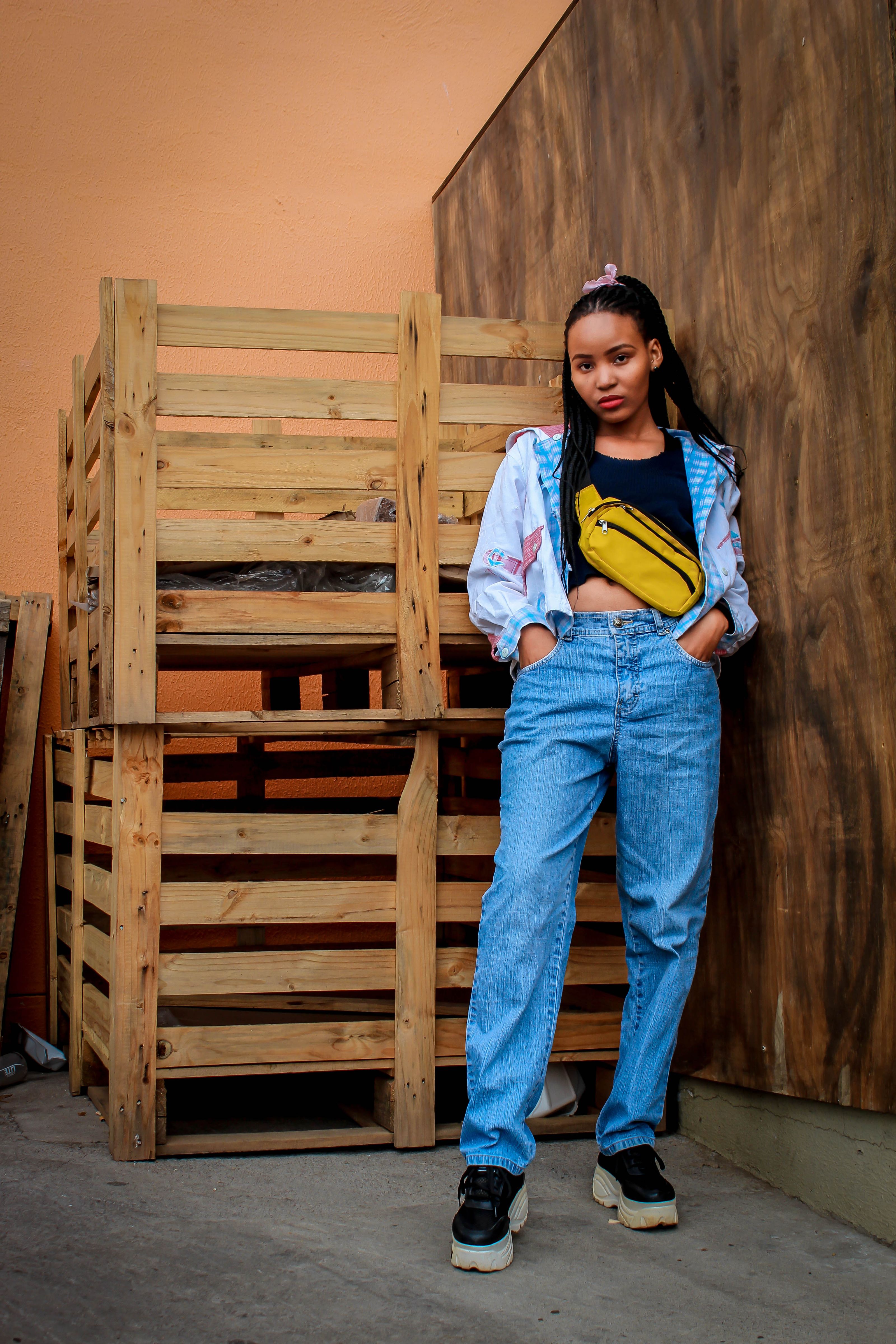 Jovem mulher estilosa posando de jeans e tênis com uma bolsa vibrante amarela.