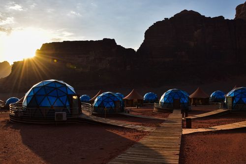 Free Experience the stunning sunrise over the unique geodesic domes at Wadi Rum's desert camp. Stock Photo