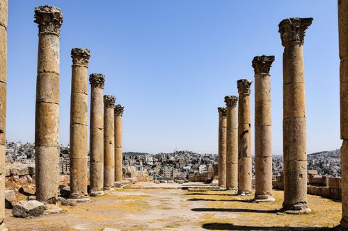 Free Historic Roman columns in Amman, Jordan with cityscape backdrop under a clear sky. Stock Photo
