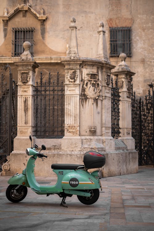 Motor Scooter Parked near Vintage Fence